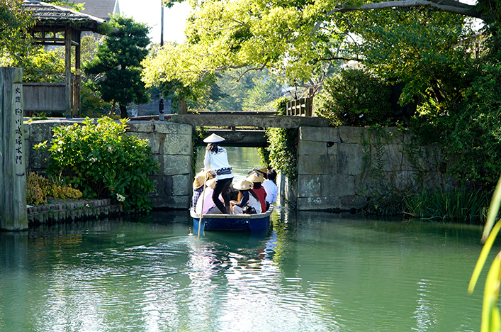 A group of people floating along a river in a traditional boat
