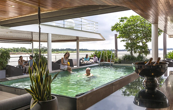 A couple swimming in an outdoor pool on the deck of a luxury river cruise ship