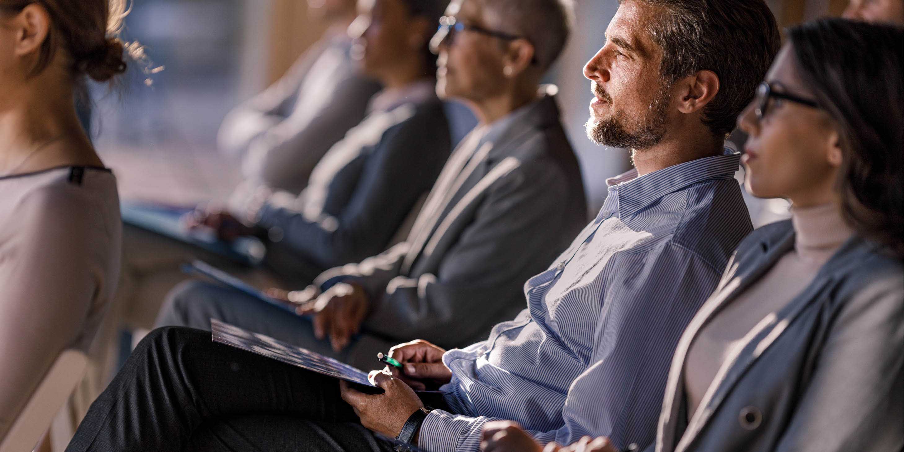 group of people sitting down wearing business attire watching a lecture
