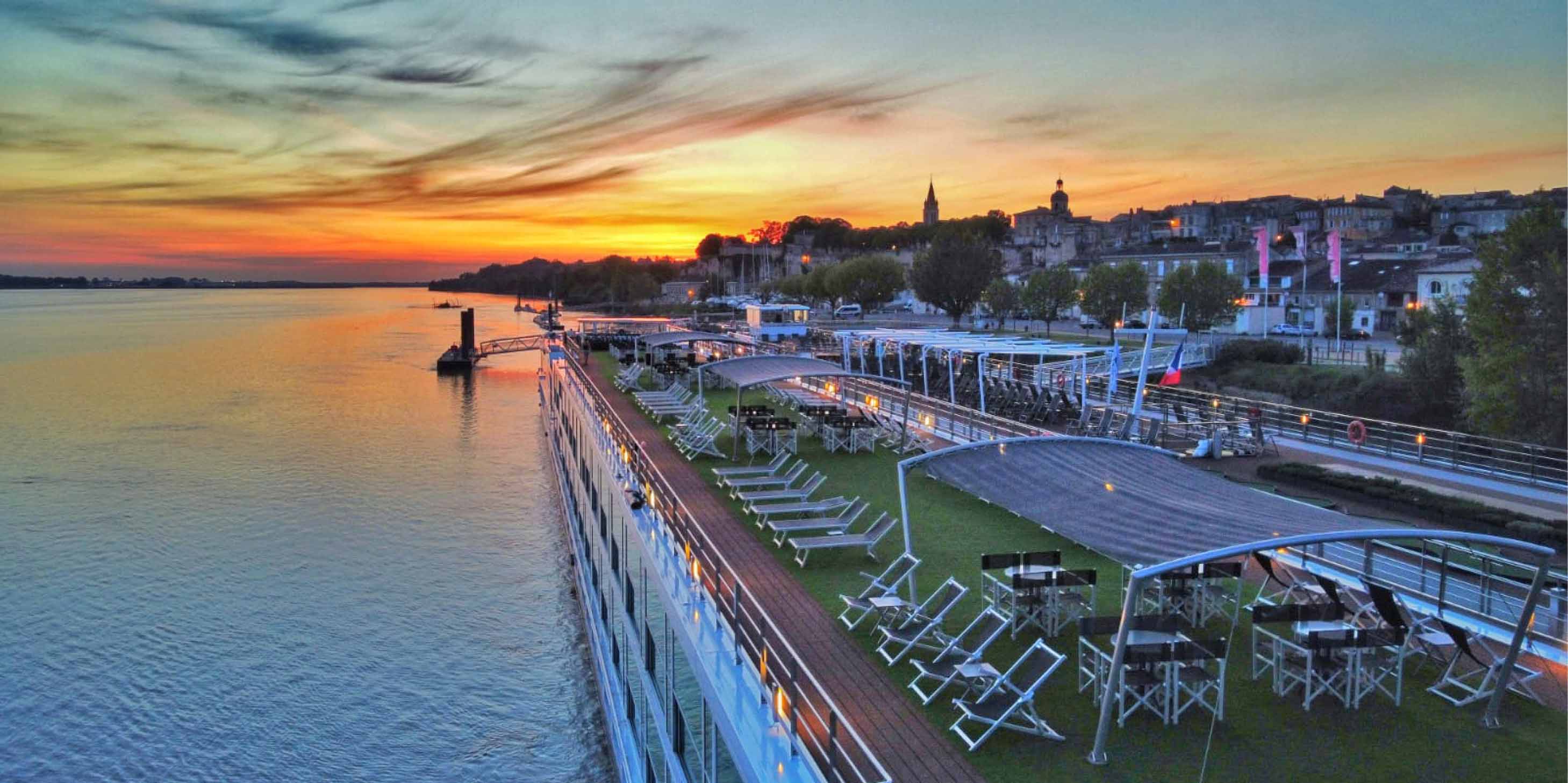 luxury river cruise ship sailing down a river at sunset