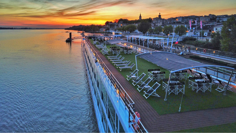 luxury river cruise ship sailing down a river at sunset