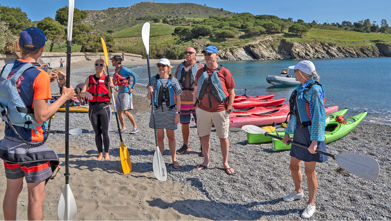 group of people listening to an instructor about sea kayaks