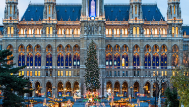 Christmas tree in front of Vienna's Parliament Building, adorned with colorful lights and ornaments.
