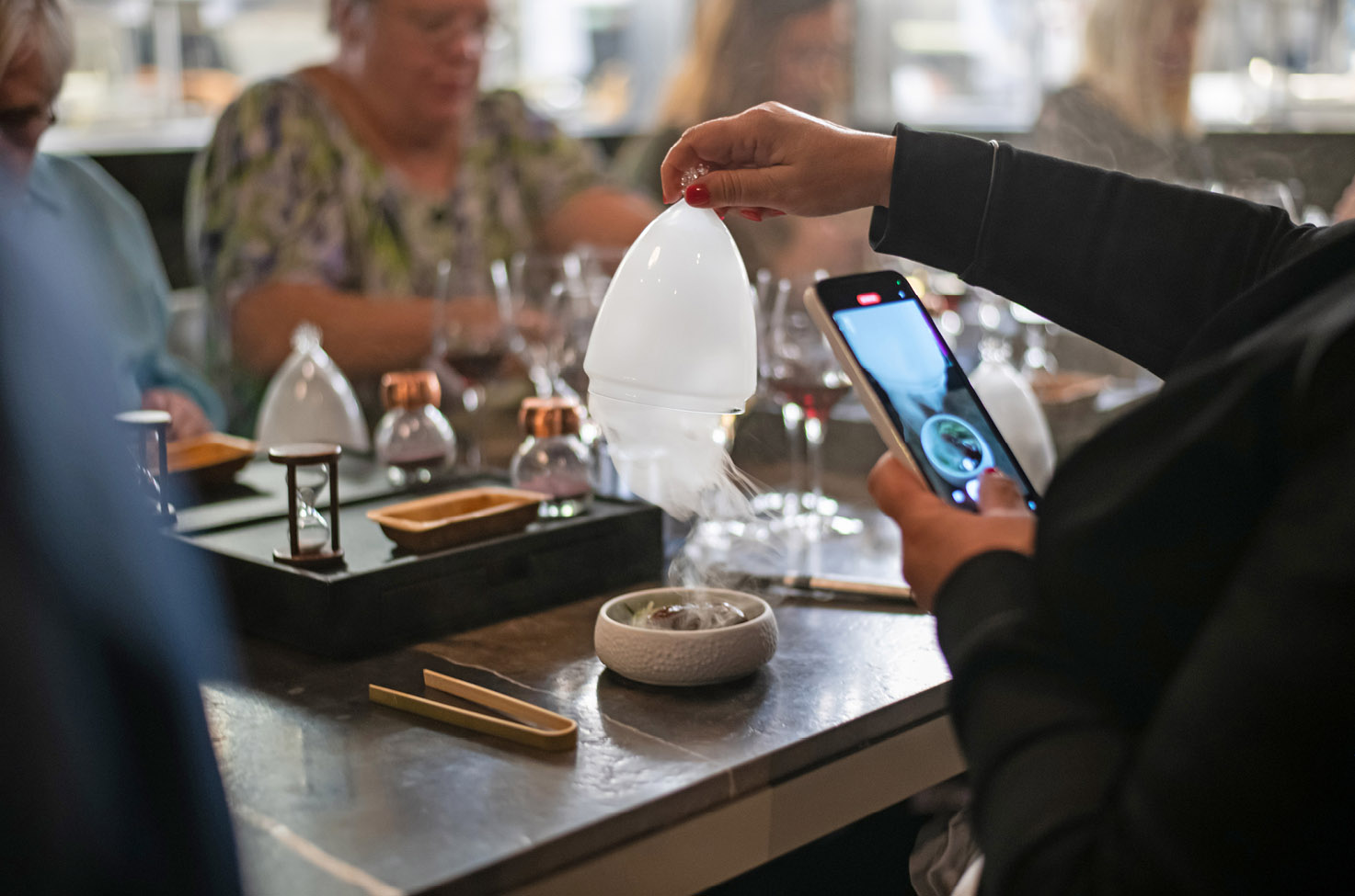someone filming a video of them lifting a dome with dry ice under it from their meal